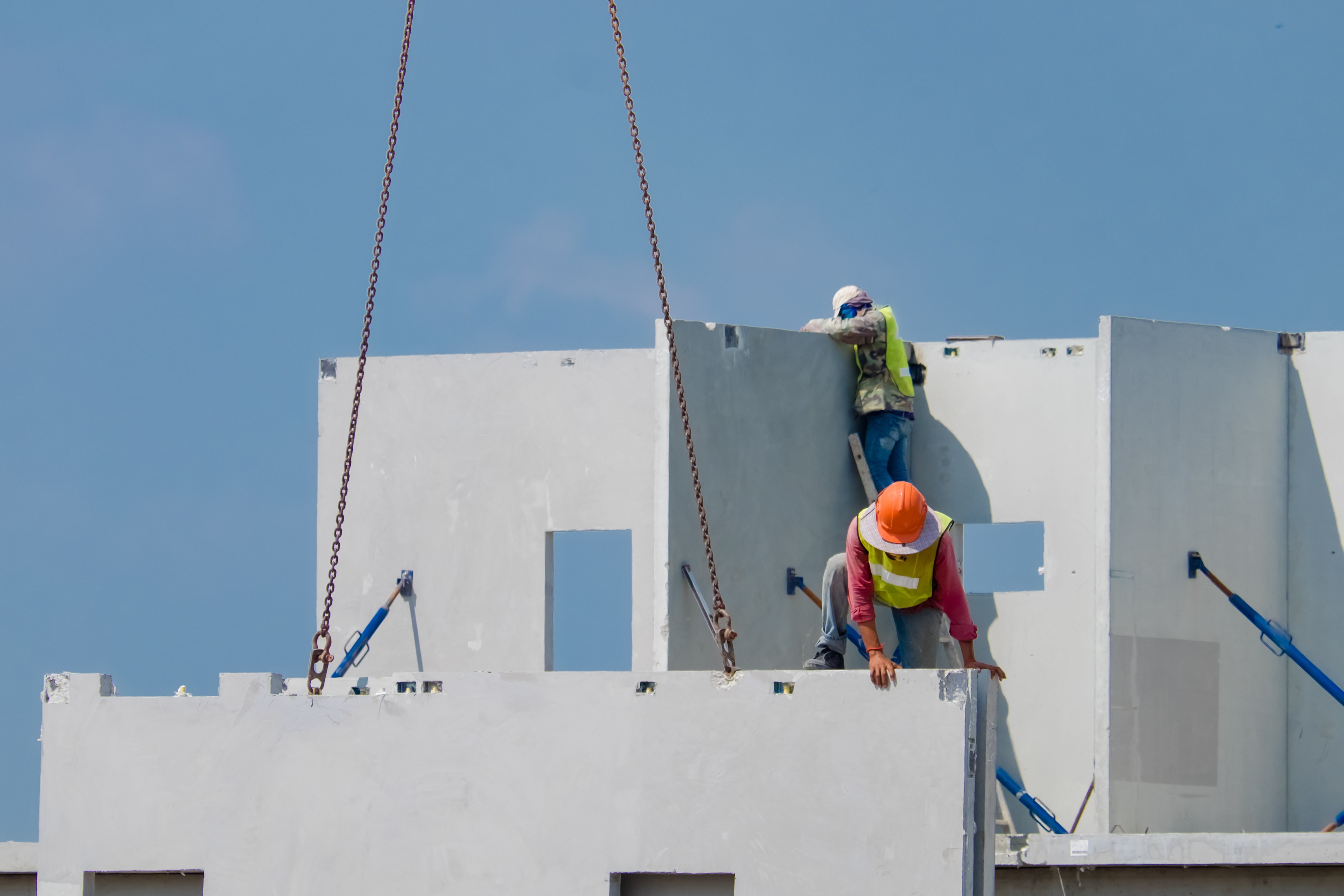 Construction workers move precast concrete panels into place on a construction site